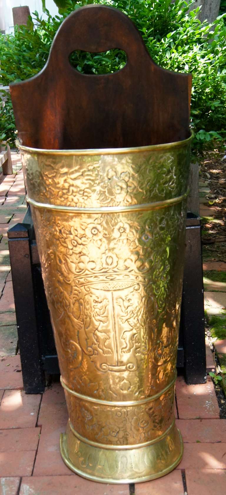 A nicely decorated brass umbrella stand with carved mahogany back.
