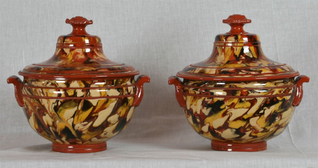 A fine late 18th century English matched pair of slipware covered tureens beautifully decorated in a marbleized pattern on a rust colored ground.