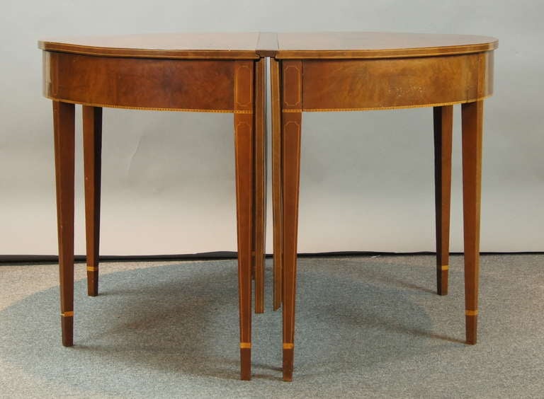 A late 19th century Federal style cherry wood dining table with deep drop leaves and two demi-lune ends on square tapering ends with satinwood banding on apron and legs.
