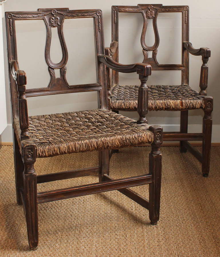 A charming pair of carved and painted walnut armchairs with old, thick rush seats.