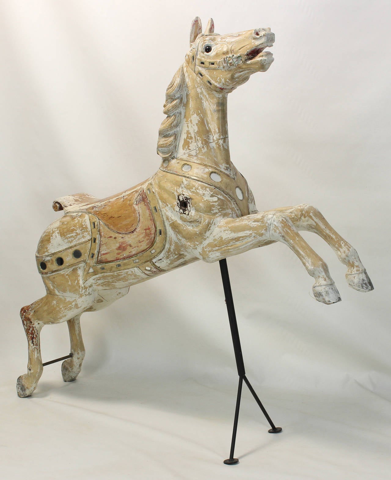 A large and charming carved wood carousel horse from a Long Island merry-go-round dating from the early 20th century. The horse retains traces of original paint as well as original inset mirror accents