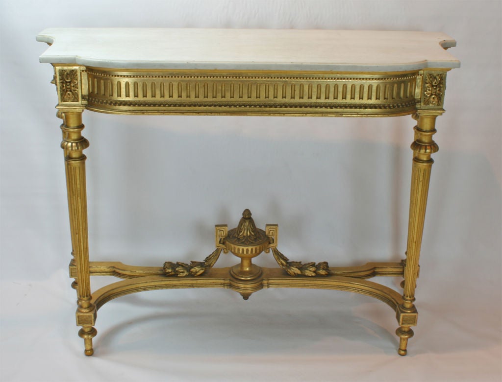 A large Louis VXI style giltwood console table. The table features a beautifully carved frieze, fluted legs and a decoratively carved and foliated urn resting on stretchers.