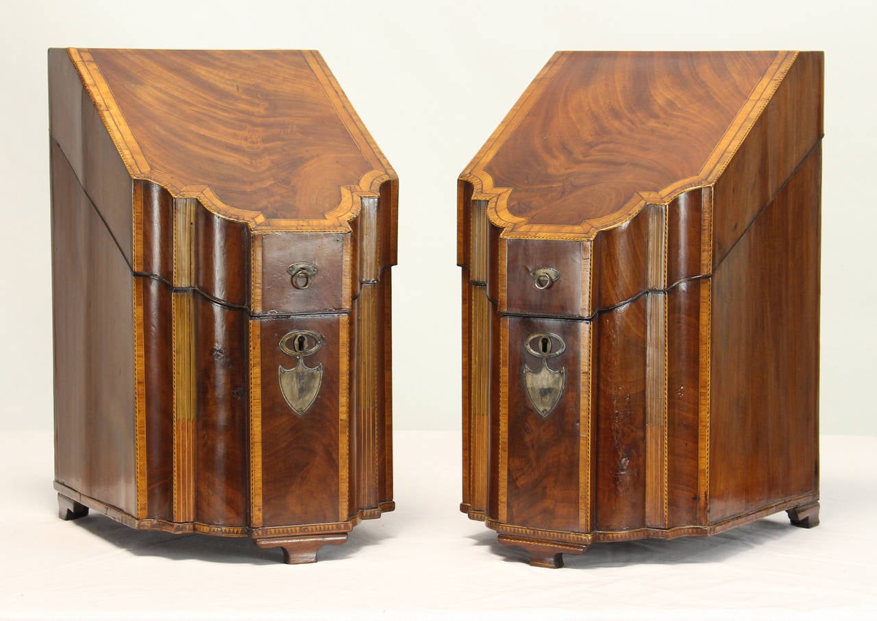 A very fine pair of George III period serpentine beautifully figured mahogany knife boxes with fine chequered ebony and boxwood accents and silver plated escutcheon and ring handles. The interior is inlaid with star decoration and painted.