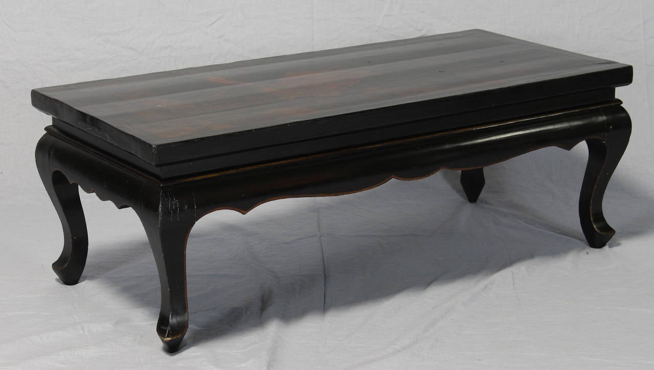 An elegant late 19th century black lacquer low-slung cocktail table with gilt chinoiserie decoration.