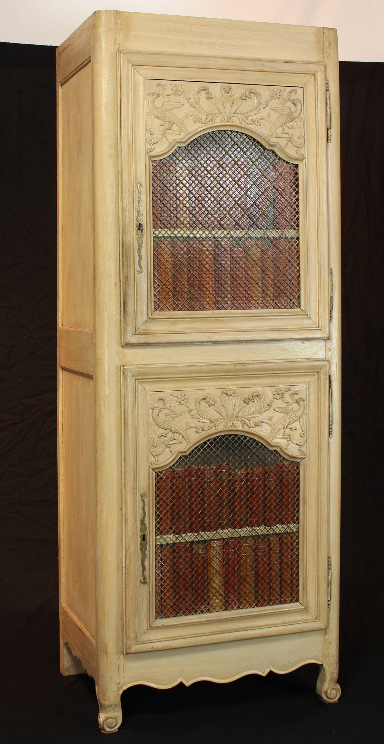 A 19th century French cabinet with two carved and faux painted doors accented with brass grillwork. The cabinet has beed converted to accommodate a television and associated equipment.