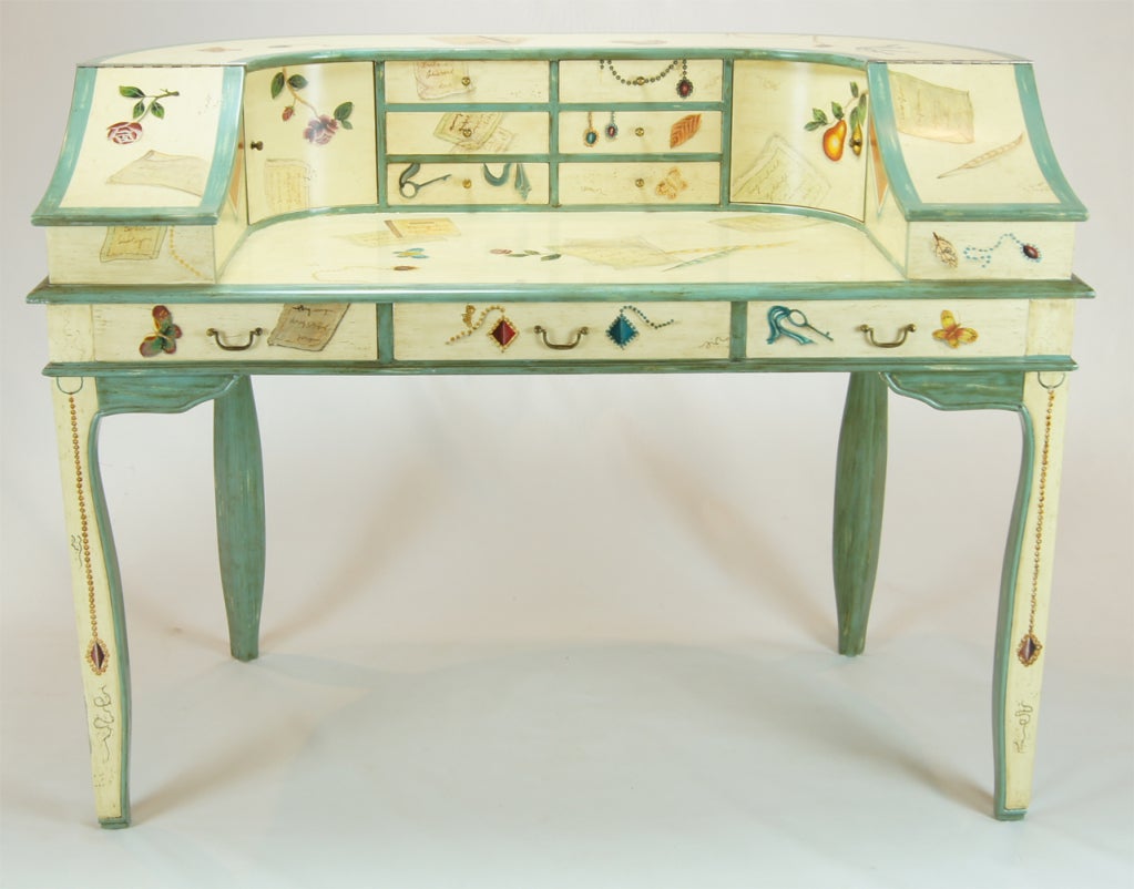 A charming tromp l'oeil painted desk decorated overall with jewelry, butterflies, fruit, flowers and a variety of other subjects. There is a generous work surface and numurous drawers and compartments for storage.