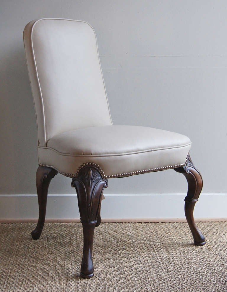 A stylized George III side chair dating from the 1930's covered in cream colored leather and accented with brass nail heads. The beautifully carved mahogany legs add greatly to the overall charm of this piece.