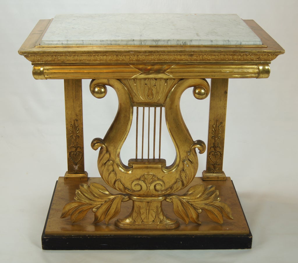 An elegant French gilt-wood pier table with lyre motif resting on an ebonized base and original mellow grey marble top.
