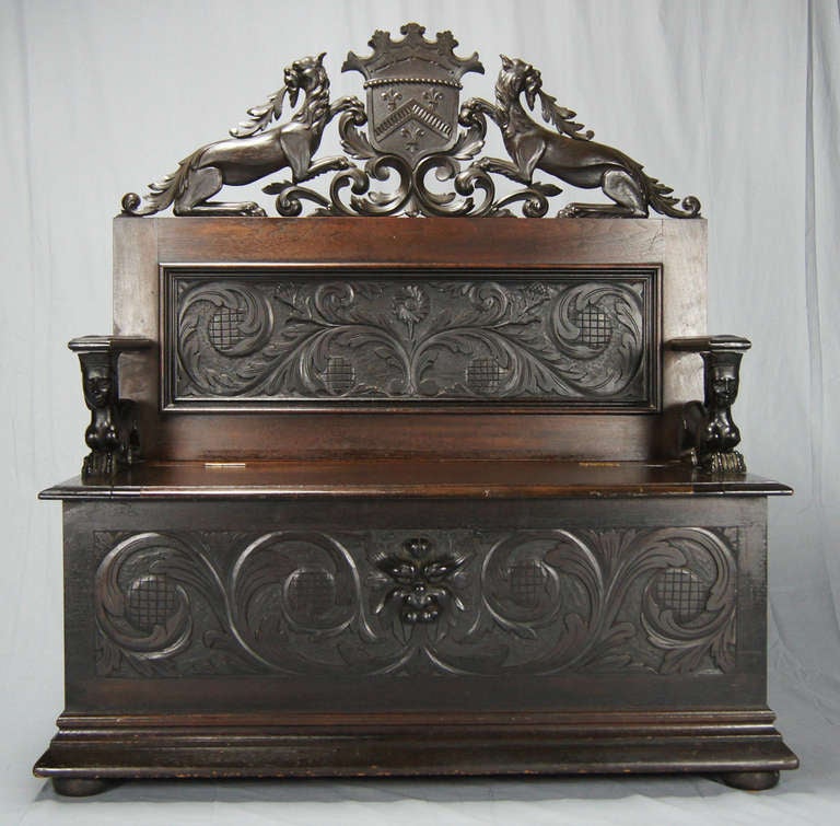 An intricately carved Renaissance Revival walnut hall bench.
The crest and back displays griffins, flowers, swags and masks and the arms are recumbent sphinxes. The seat opens to a large storage space.
