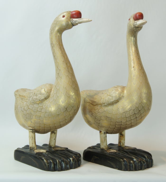 A delightful pair of life-size geese fashioned from carved wood with old gilt decoration and accented with ivory bill and feet.