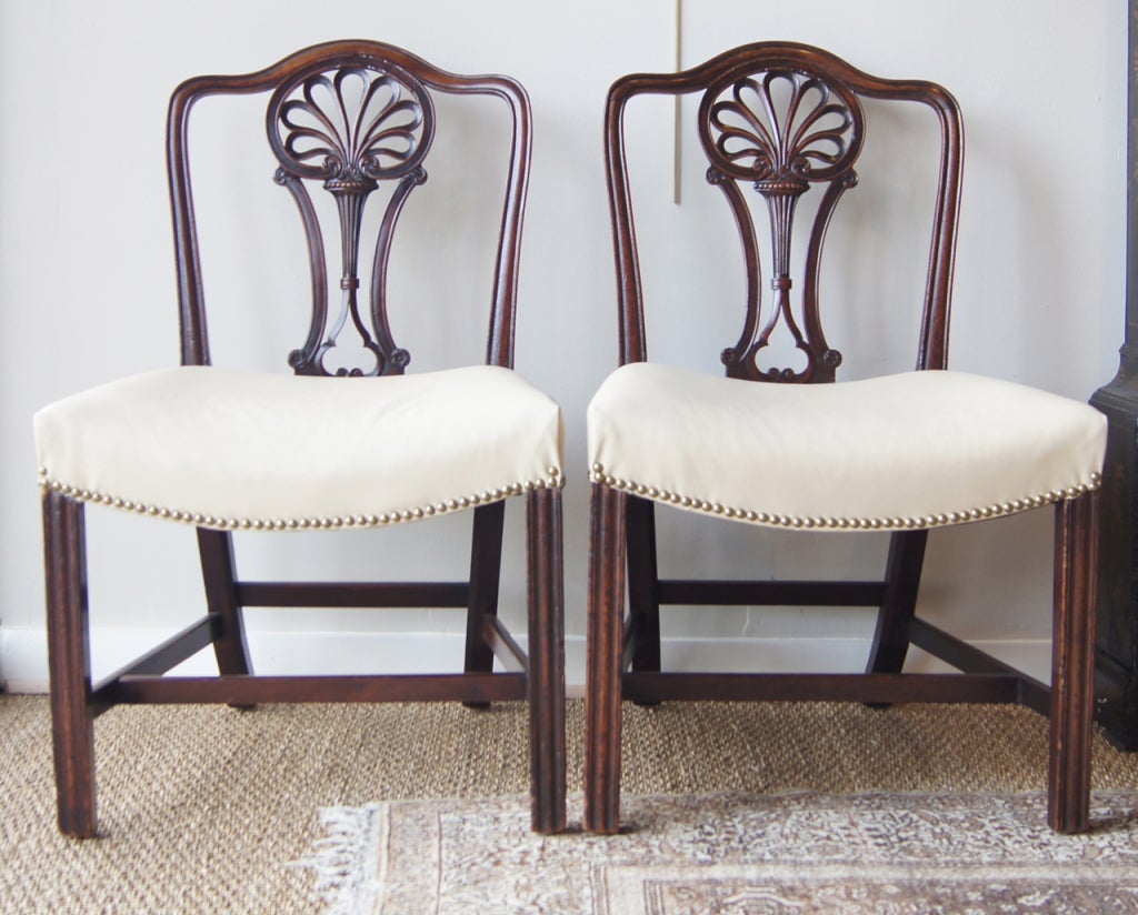 An elegant pair of George III mahogany side chairs with pierced and carved panel backs, stuff over hollow seats and molded square section front legs linked by H stretchers.