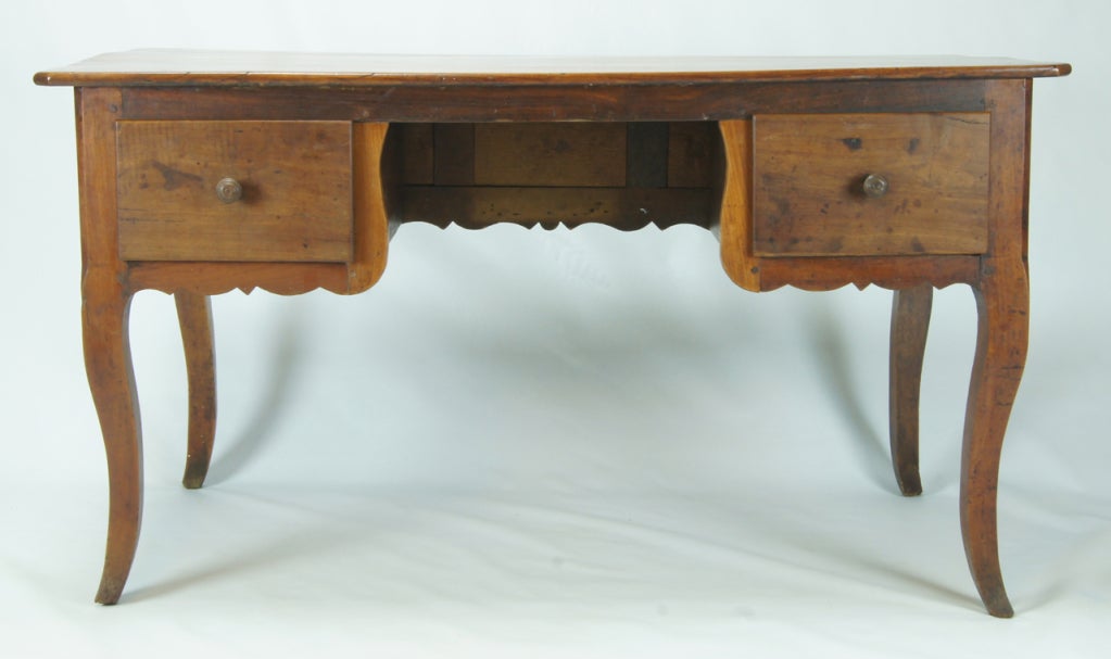 A large and charming country French desk made entirely of cheerywood. The beautifully paneled back side allows the piece to float in a room or be used as a console table against the wall.