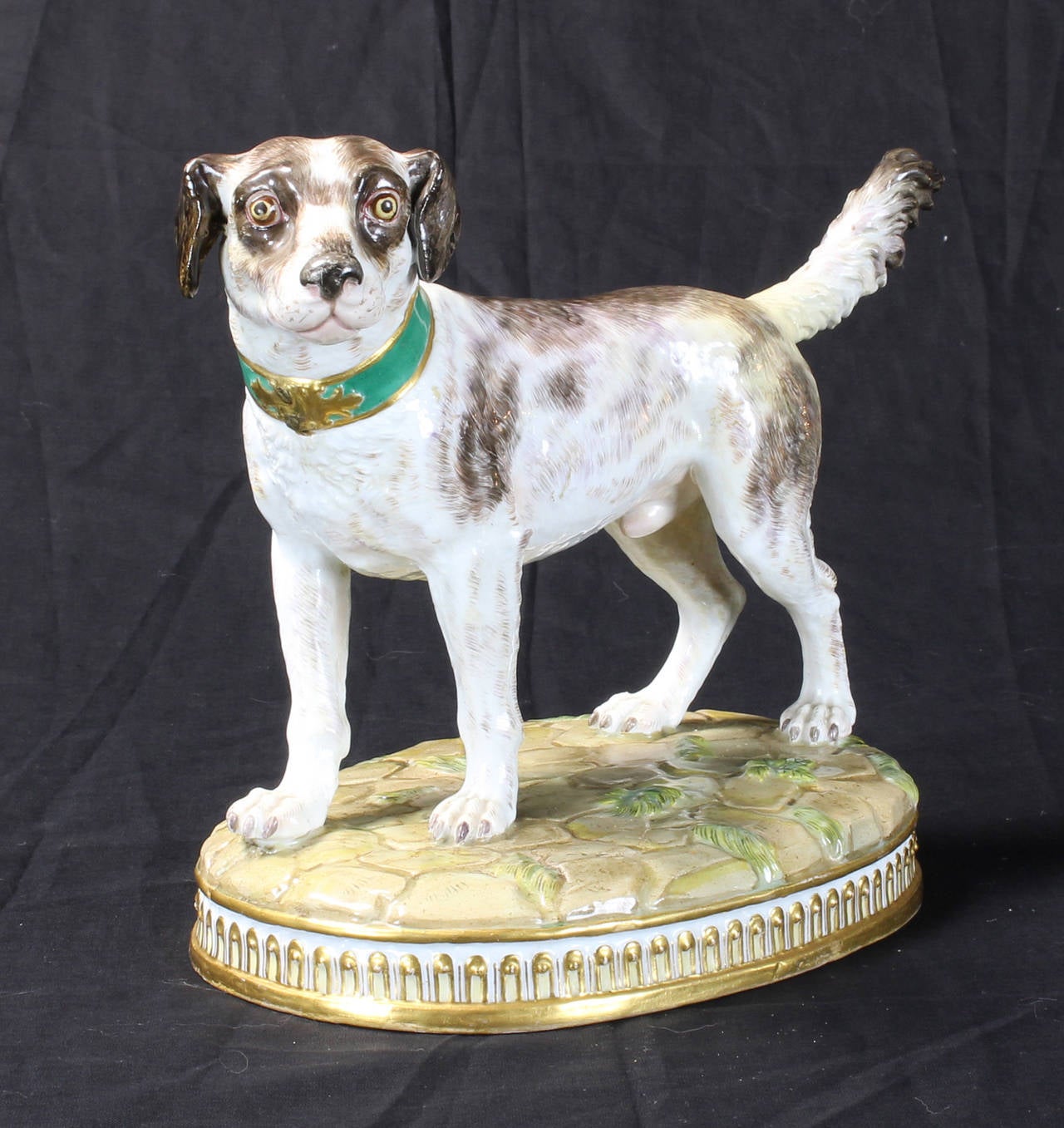 A large early 19th century Meissen model of a hound raised on an oval mounded base, crossed swords mark and 