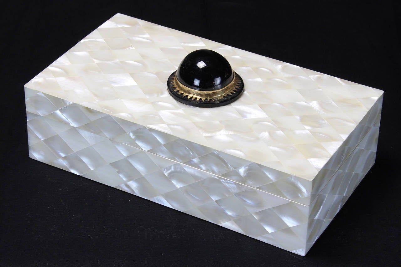 A mother-of-pearl box set with a large black cabochon stone with bezel.