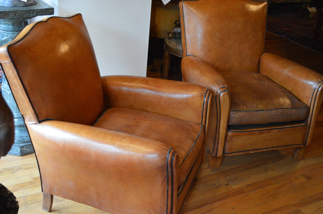Pair of French leather Art Deco club chairs, mustache form, ebonized piping, beechwood frame.