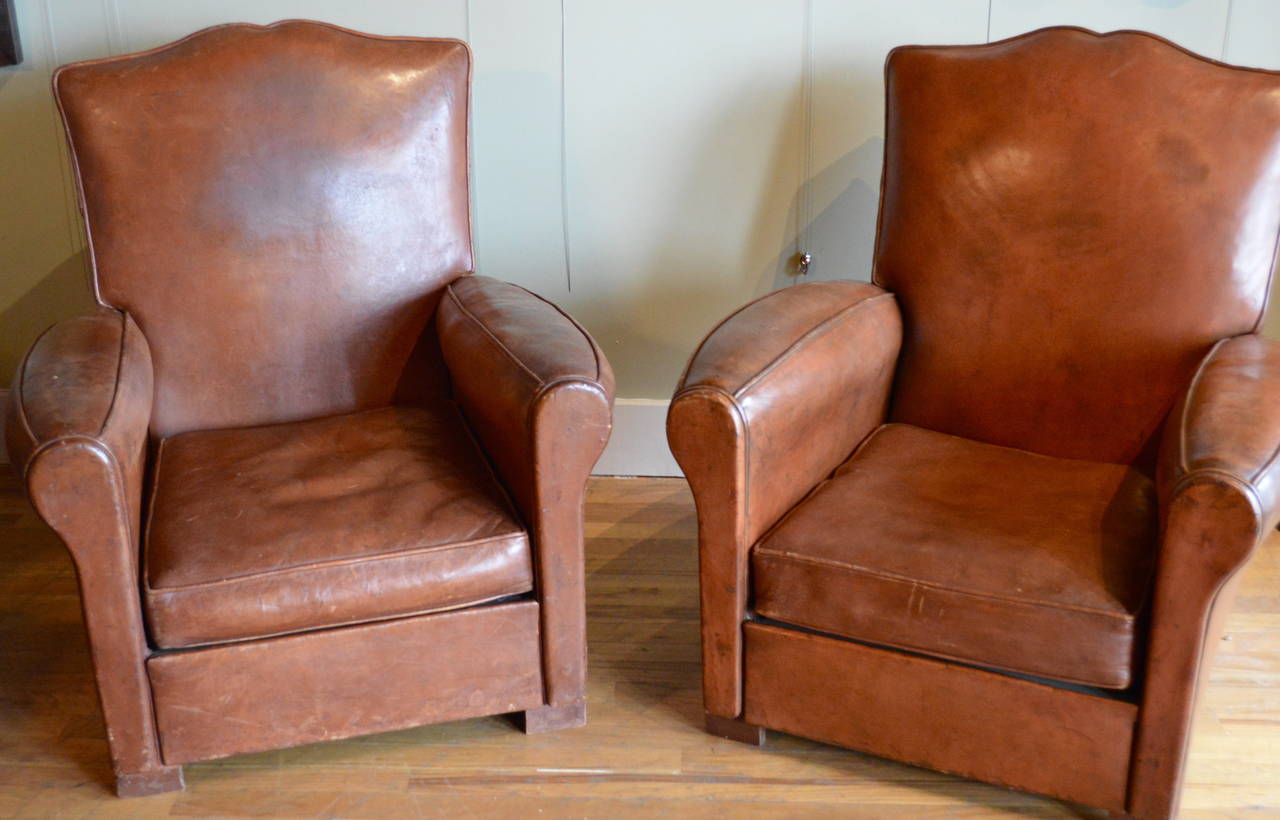 Pair of leather Art Deco club chairs, mustache form.