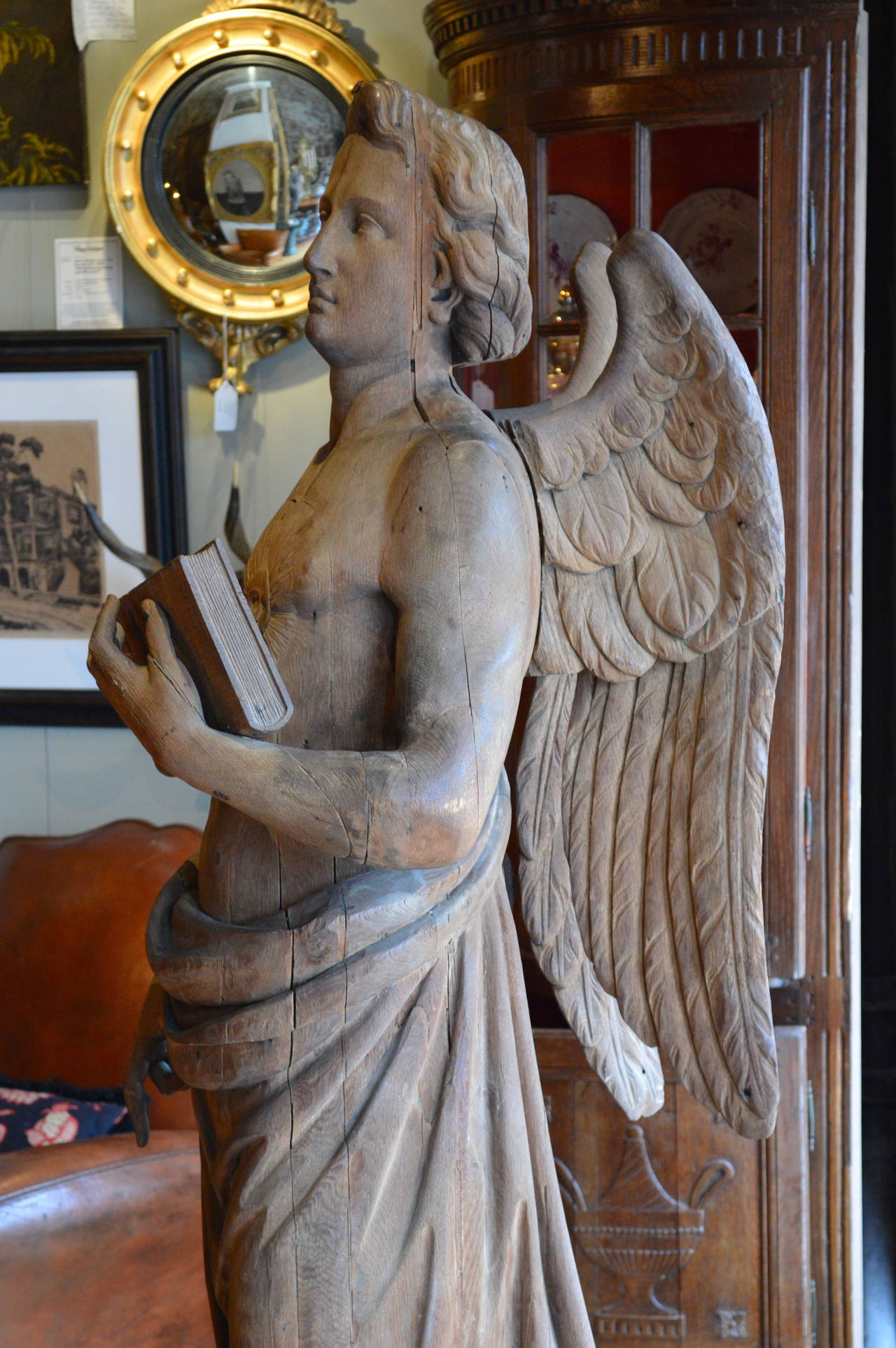 19th century carved figure of Archangel St. Uriel in laminated and carved white oak, unusual carving of sun medallion on chest with attached wings, Book represents wisdom, probably carved for Anglican church probably from England, found in Wisconsin.