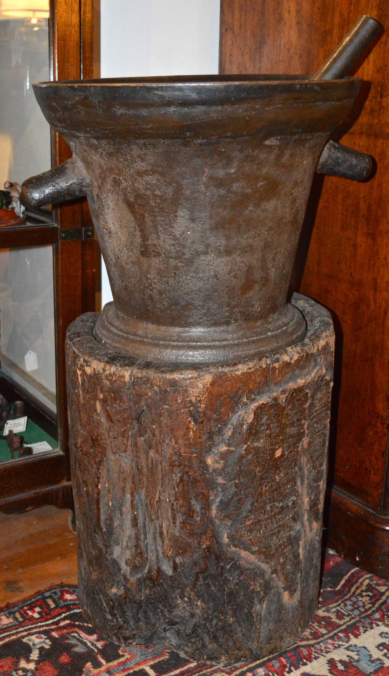18th century unusually large cast iron mortar and pestle on a rough hewn tree stump with leather and wood cover. Probably an apothecary trade sign. Found in France.