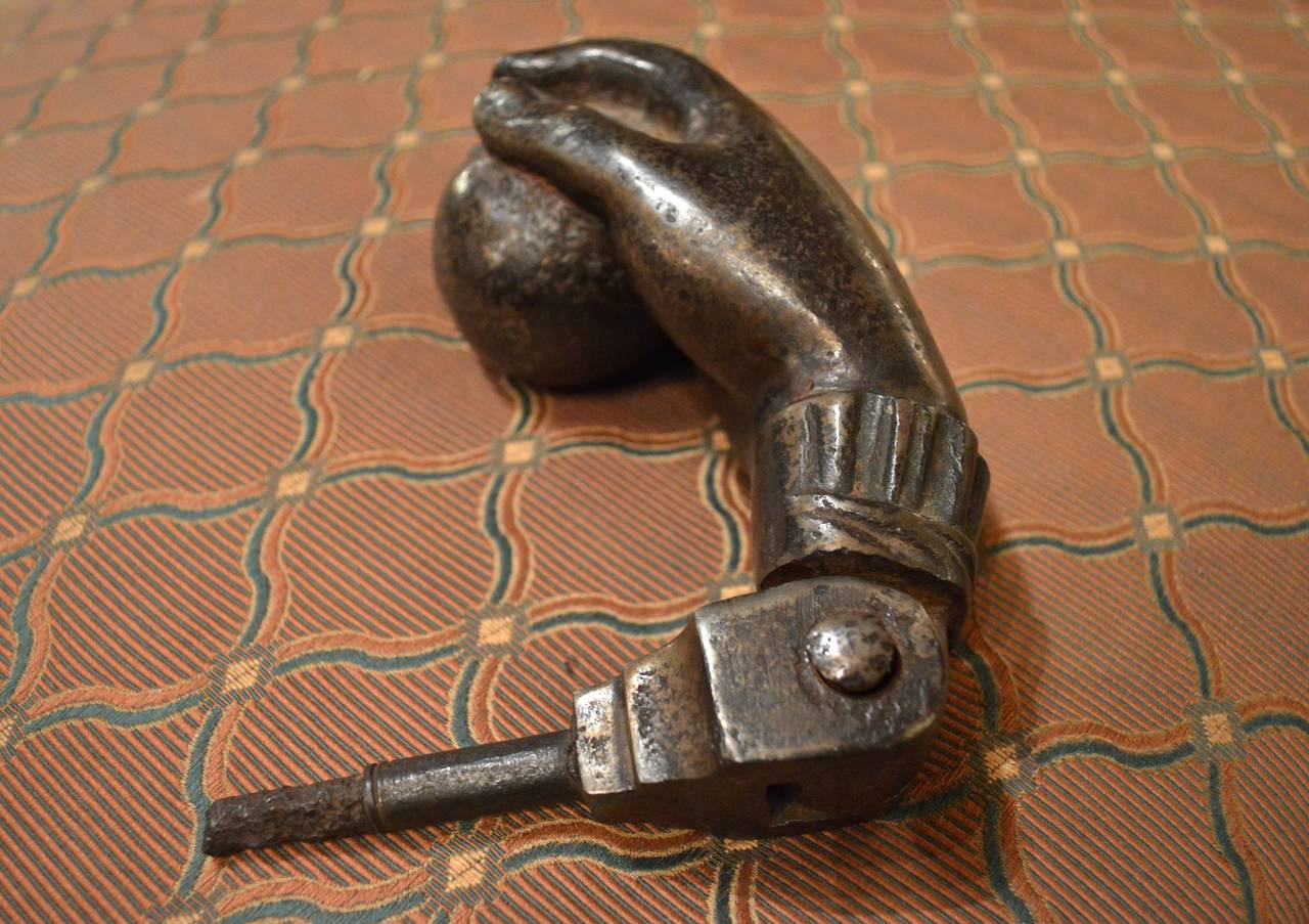 19th century French cast iron door knocker in the form of a hand holding a ball with ruffled collar.
