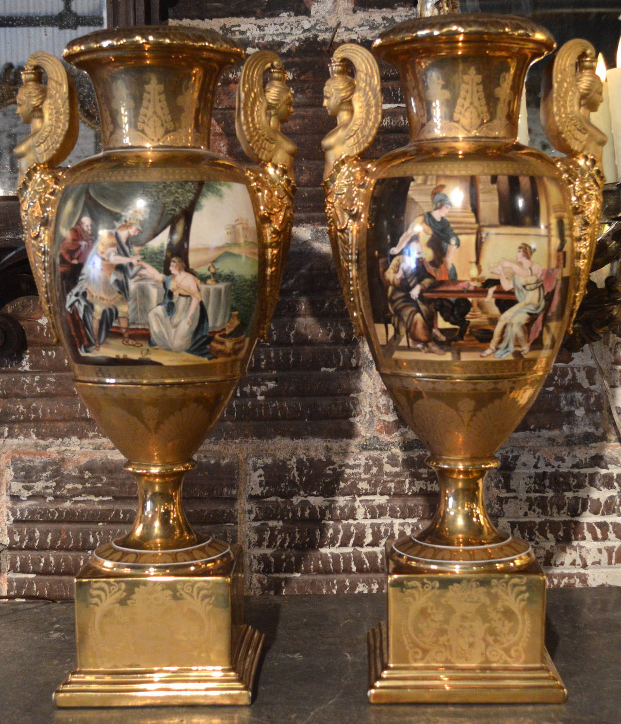 Pair of fine French neoclassical style porcelain baluster form vases with square plinth bases and applied winged classical female form handles, front-facing hand-painted paneled scenes of Romanesque classical figures with gilt overlay floral