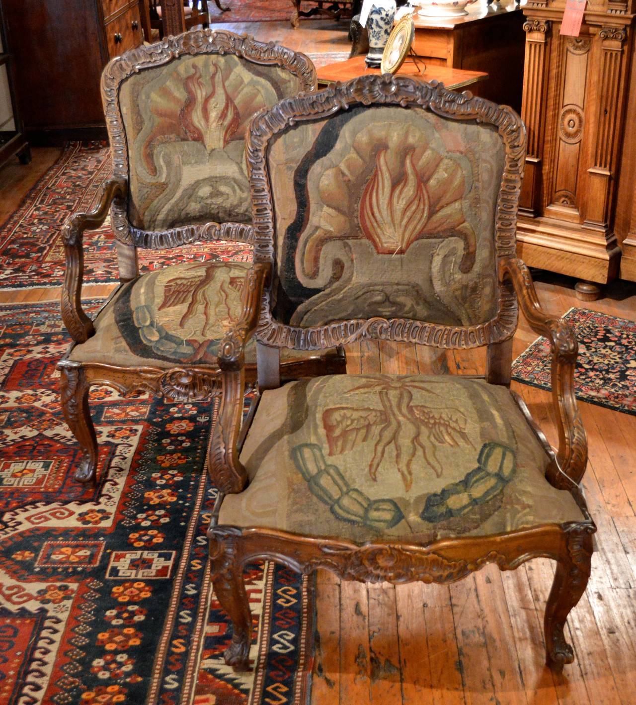 Pair of finely carved walnut Louis XV style Rococo fauteuil a la reine with beautiful 18th century needlepoint upholstered seats and backs, unusual motif possibly masonic.