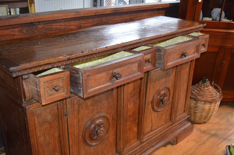 A handsome Italian Walnut 17th century Tuscan credenza with a plank top bordered  by dentil molding over five various size drawers over two center doors with an interior shelf.  Beautiful rosette pulls on paneled doors with applied moldings.  Piece