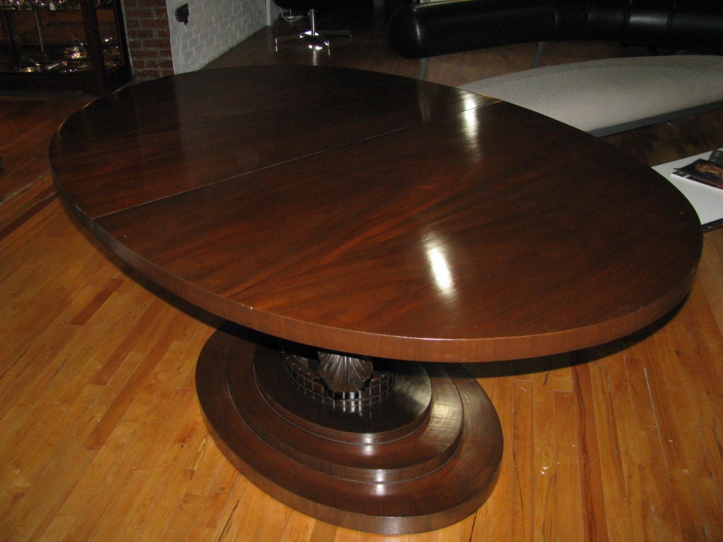 A beautiful mahogany French Art Deco dining table with stacked base and a stylized center crown with Prince of Wales feather supports. This table extends with three additional leaves.