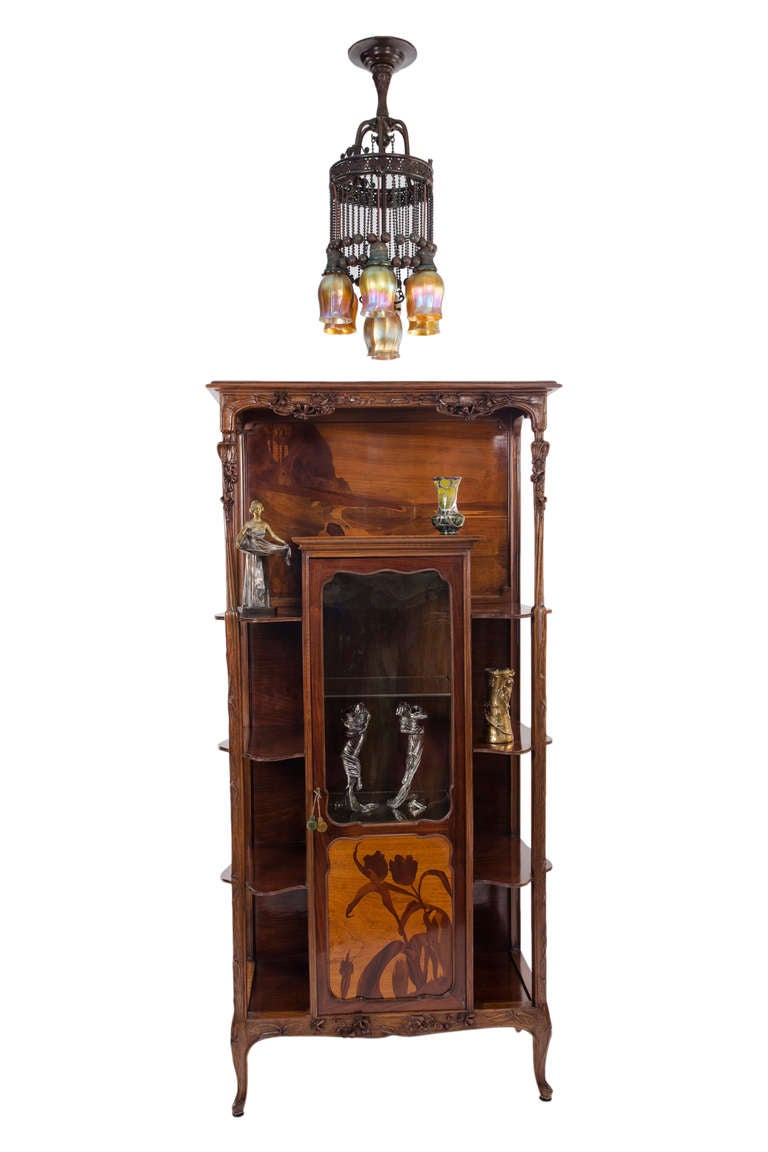 A fine and rare French Art Nouveau carved wood and exotic wood marquetry étagère by, Louis Majorelle decorated with carved flora, marquetry scenic landscape and tulip marquetry decorated door. The étagère is signed, 