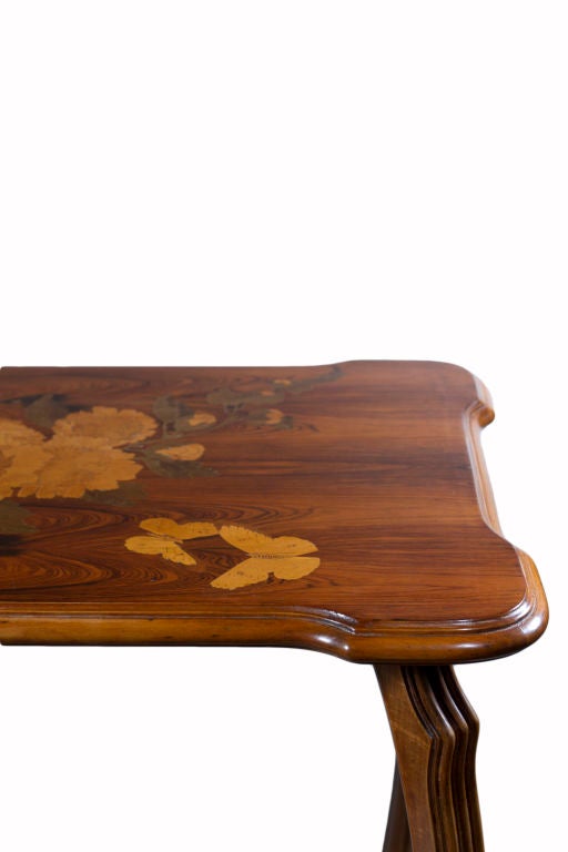 A French Art Nouveau two-tier table by Emile Gallé, featuring inlaid marquetry depicting a natural landscape of sunflowers and butterflies in a combination of rosewood, walnut and fruitwoods. The table is signed, 