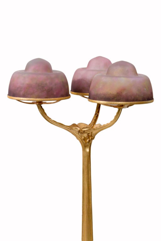 A rare and important bronze & glass table lamp by, Louis Majorelle decorated with three matching colored glass shades by, Daum fréres a top a decorated gilt bronze base by, Louis Majorelle. The shades are signed, 