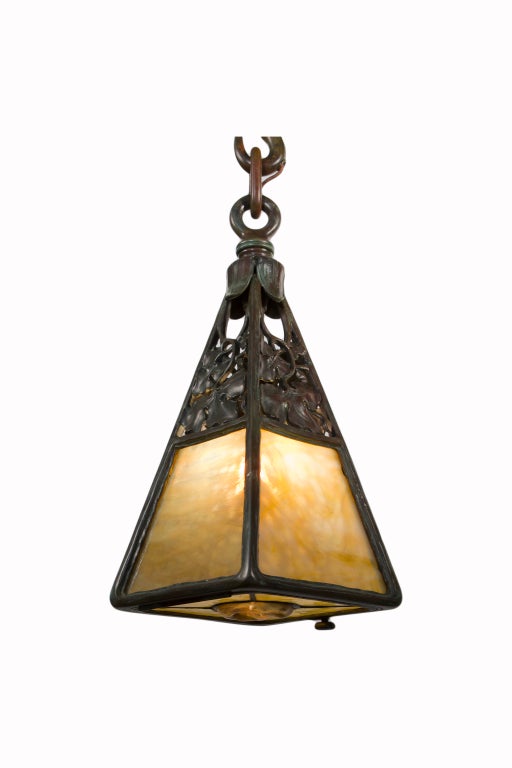 An American Art Nouveau patinated bronze and stained glass lantern by, Tiffany Studios with pierced bronze leaf and vine decoration with four mottled carmel - yellow stained glass panels and further decorated with a stained glass and turtleback tile
