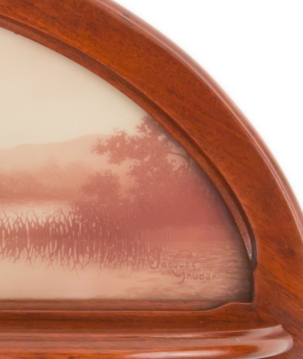 A rare French Art Nouveau carved mahogany and glass wall shelf by, Jacques Gruber decorated an acid etched purple against white lakeside landscape set with in the shelf's backboard. The glass is signed, 
