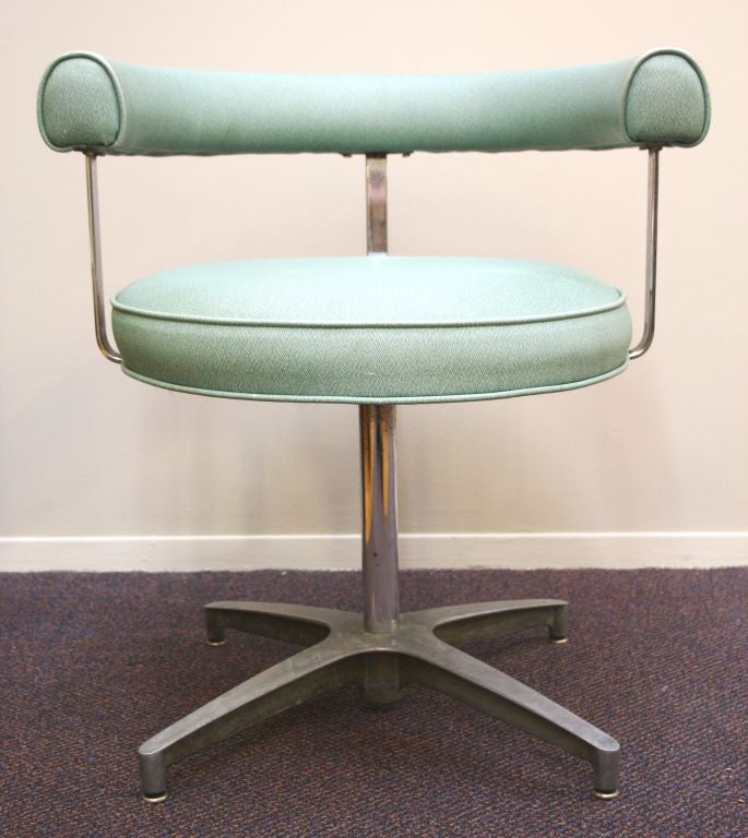 A pair of mid century round back swivel chairs on steel x-form pedestal bases. Each is upholstered in a pale teal vinyl upholstery.