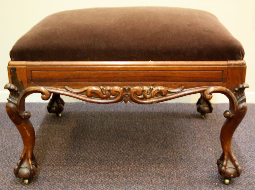 An antique rosewood bench with brown velvet upholstery. The piece has intricately carved scrolling and cabriole legs that end in a claw and ball foot with brass casters. The piece bears the name "Thornton" underneath.

Reduced From: