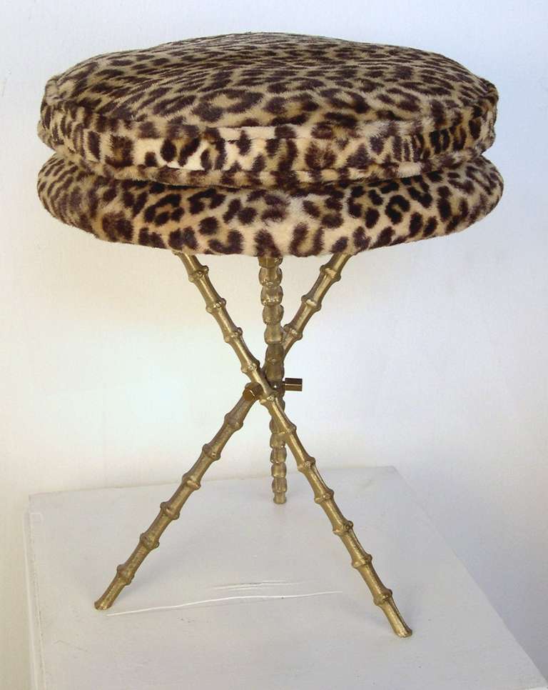 A vintage stool by Piero Fornasetti with a leopard print cushion and brass faux-bamboo tripod base. It is labeled Fornasetti underneath.