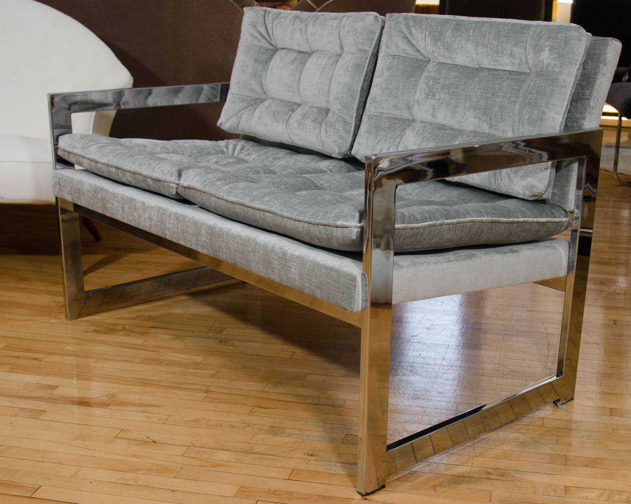 A mid century loveseat, in the style of Milo Baughman, with chrome frame and newly reupholstered in tufted, grey velvet seat and back cushions. Good vintage condition condition with some age appropriate wear.