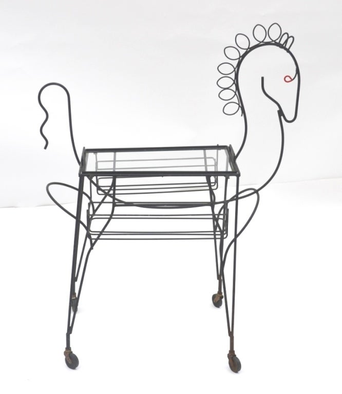 A vintage wrought iron bar cart in the shape of a horse. The piece is on casters with glass top shelf and removable side baskets.