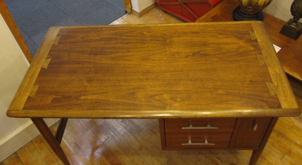 A vintage desk with drawers and classic mid century modern lines by Andre Bus for Lane. The piece has a walnut veneer top with oak edges