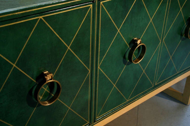 A vintage four-door credenza by Tommi Parzinger for Charak with tooled green leather-wrapped body and brass detailing.