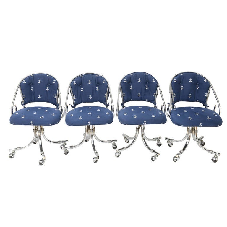 Set of four cushioned chrome rounded back chairs on casters. Upholstered in a fun navy nautical fabric with white anchors used only in showroom. They swivel and roll and can be used for office, conference, dining, and more. Chrome had been polished