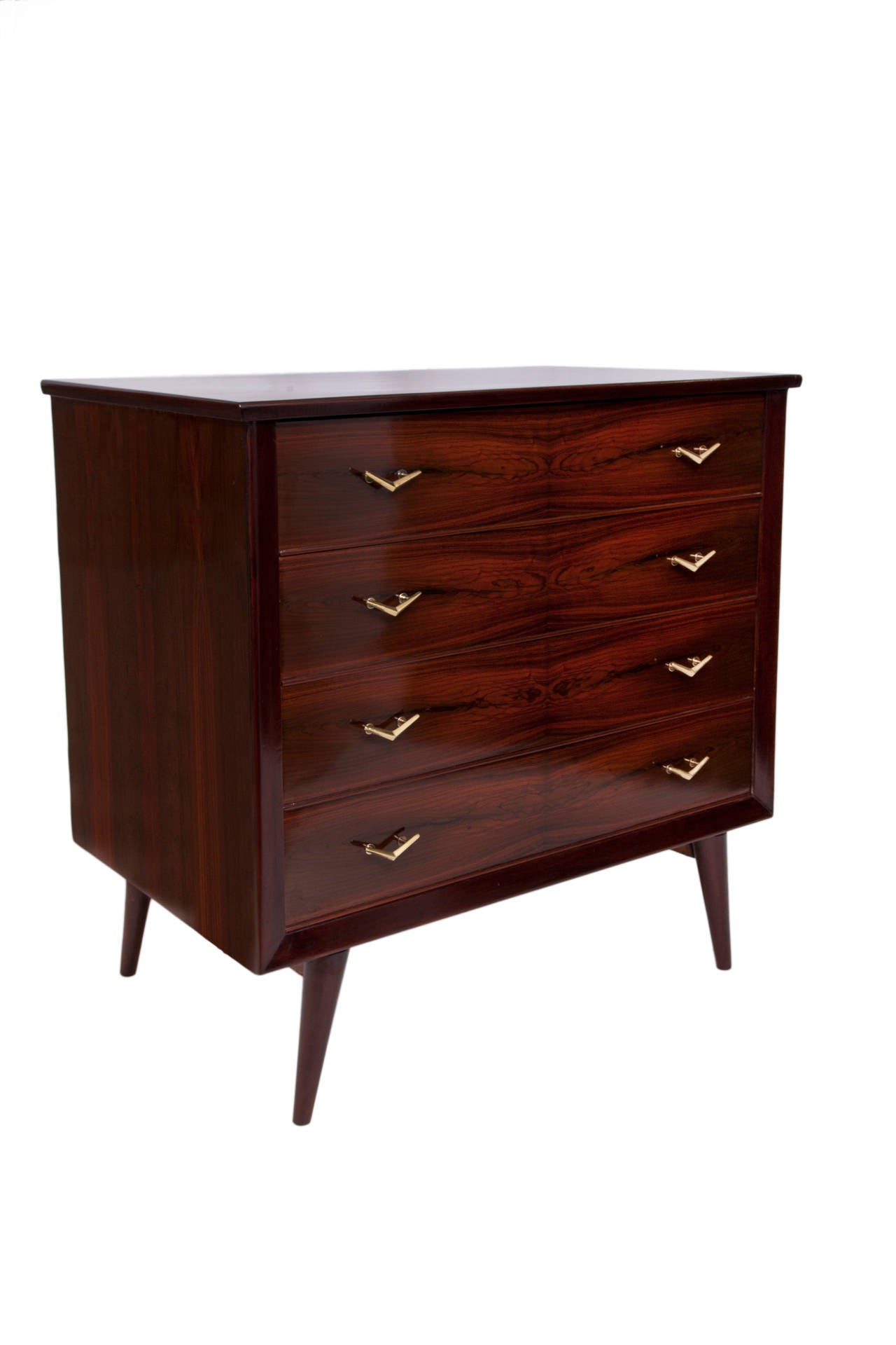 A vintage, circa 1950s four drawer dresser, in Brazilian jacaranda veneer against caviuna wood, with brass handle details, on gracefully angled tapered legs. Very good condition, consistent with age and use. 