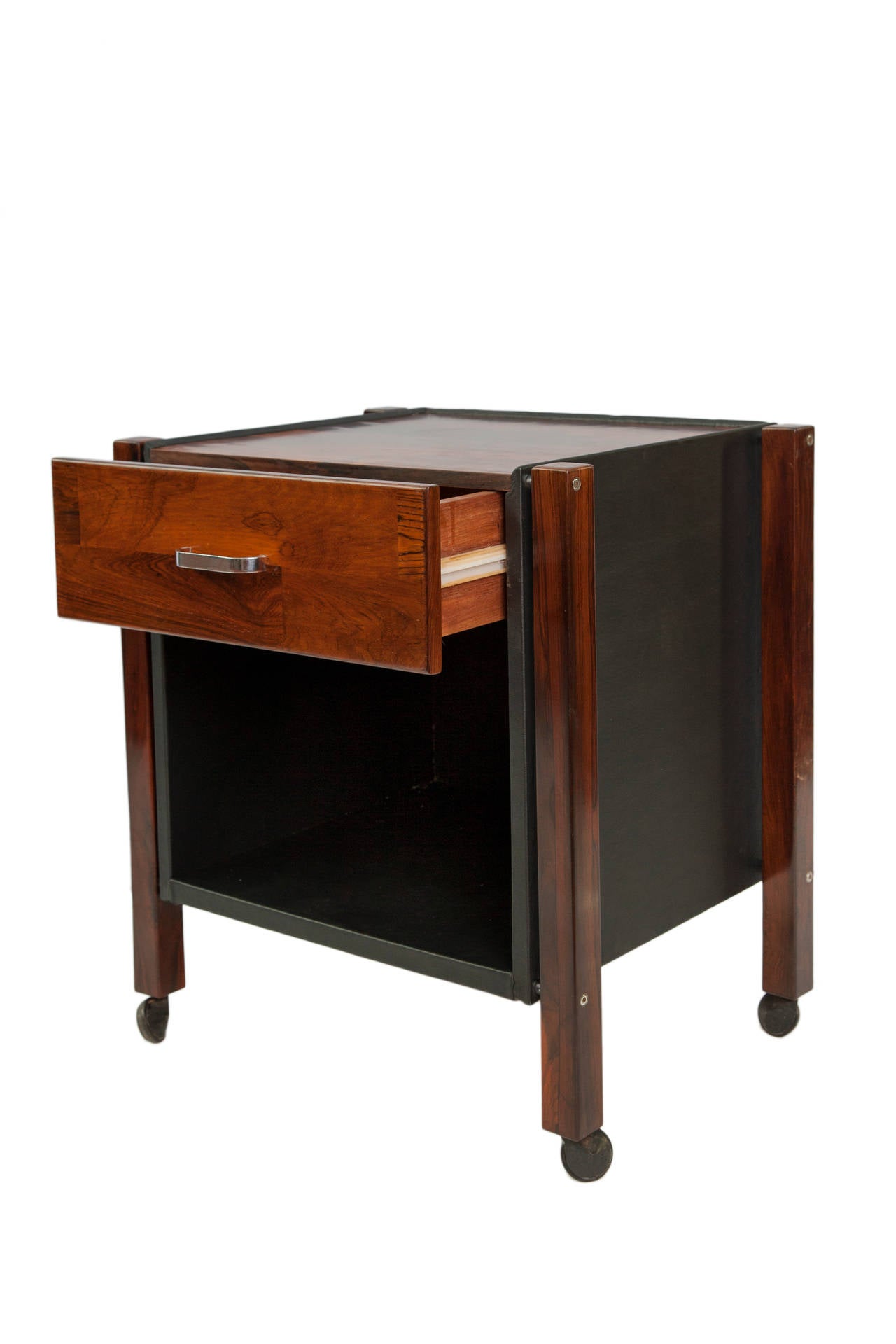 A vintage pair of side tables, produced circa 1960s, by designer Jorge Zalszupin for L'Atelier, in Brazilian jacaranda wood, each with patchwork tops, single drawers with chrome handles and black leather cases beneath, on caster wheels. Very good