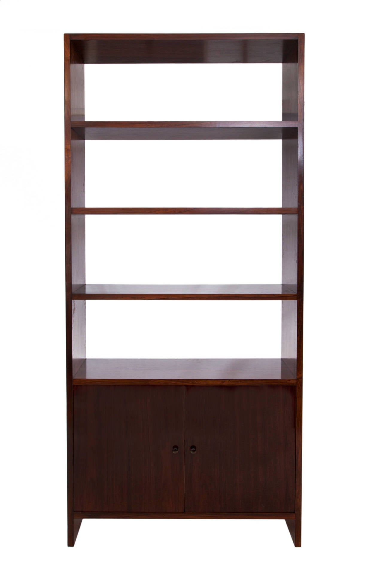 A pair of vintage, highly unique bookcases, produced in Brazil by furniture company Branco & Preto, circa 1950s, both in beautifully lacquered jacaranda wood, with shelving on two door cabinets, one of pair inset with two raised drawers. Very good