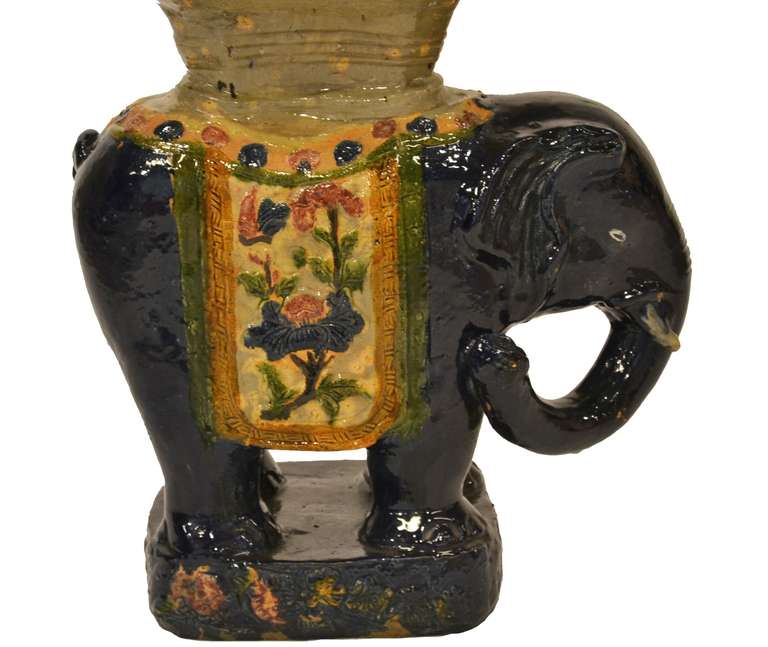 A decorative elephant shaped ceramic garden stool in dark blue with colorful floral detailing.