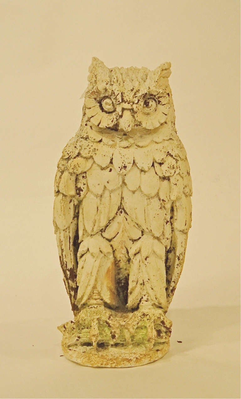 A cast stone weathered sculpture of a standing owl. It was originally part of a fountain.