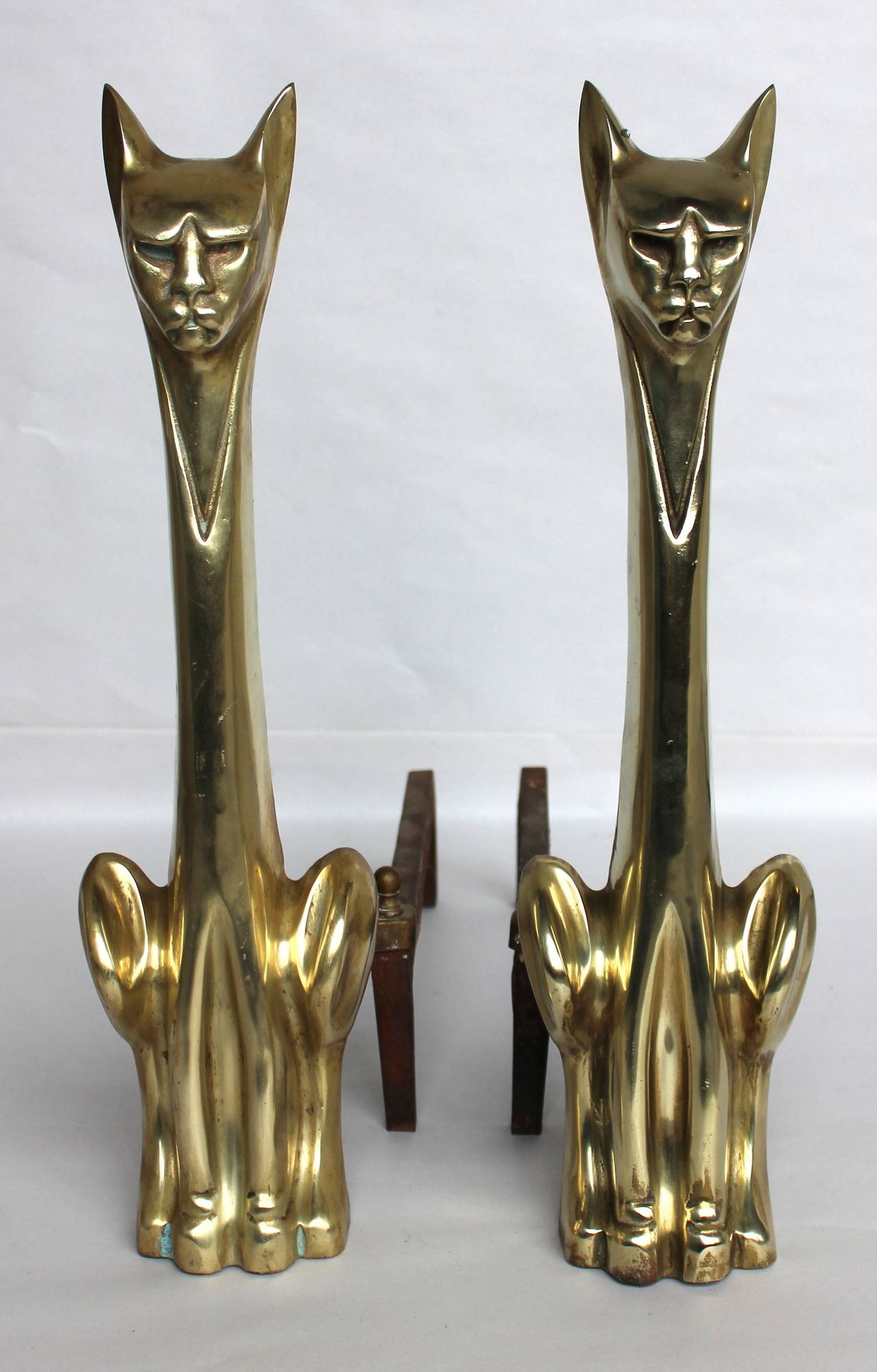 A vintage pair of andirons in the form of two stylized brass cats. Good vintage condition with age appropriate patina.