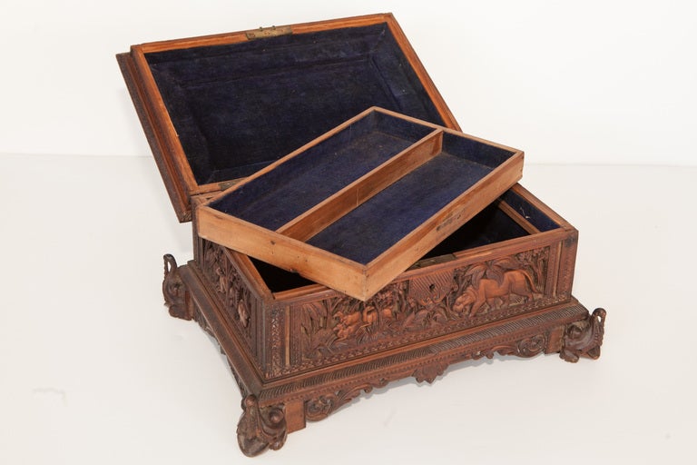 Box carved from exceptionally fragrant sandalwood from the Southern Indian city of Mysore. Each side has carvings of animals depicting scenes from Indian mythology. Feet are stylized elephants. Inside has single removable drawer box with velvet