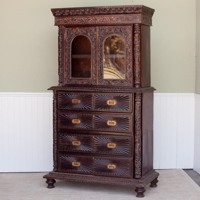 Indo-Portuguses rosewood cabinet with sections. The top half has 2 elaborately carved glass framed doors that open to a removable shelf. The bottom half (which is in 2 sections) has 4 drawers with a sunburst pattern and  brass handles. Each part is