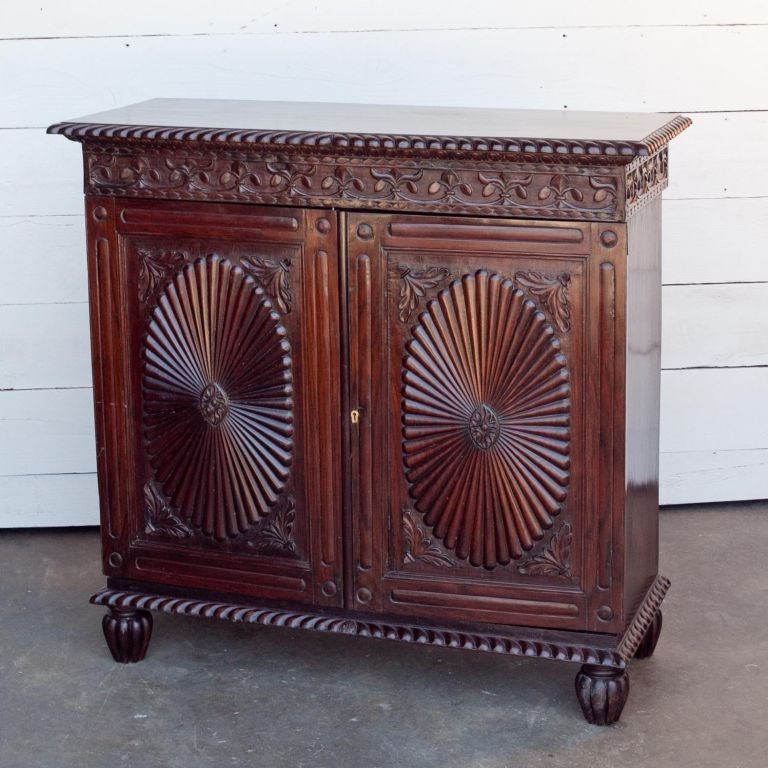 This is a mid 19th century cabinet with a pair of well-carved and detailed sunburst door panels . It has a solid rosewood top with a gadroon edge moulding all around it and has carved melon feet at the base .Comes with 2 removable wood shelves.
