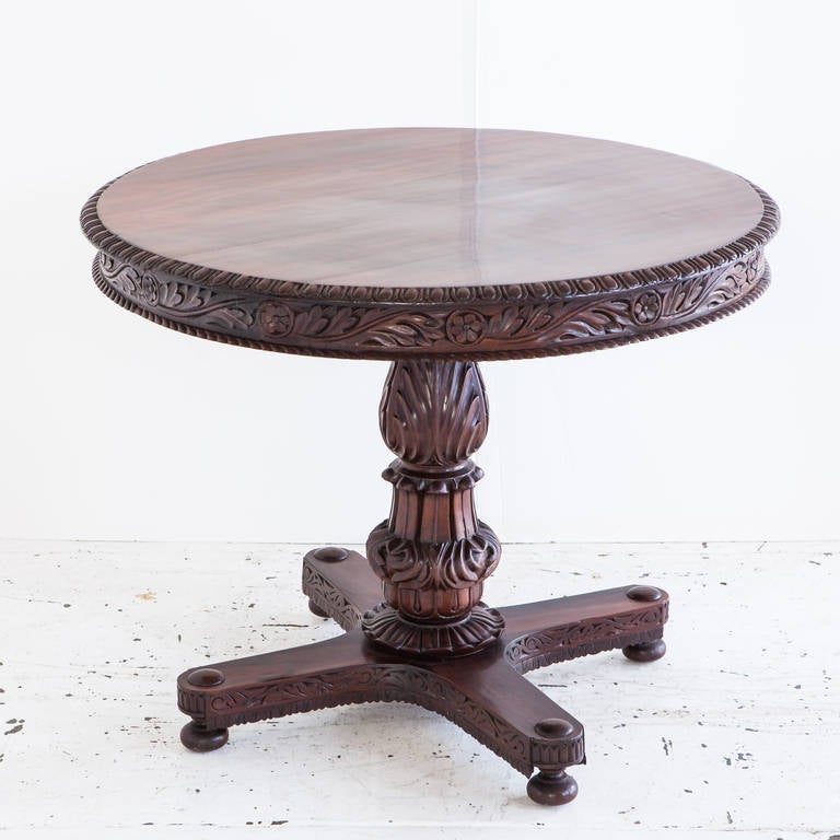 Anglo-Indian rosewood tilt-top center table with carved details on base and skirt. 